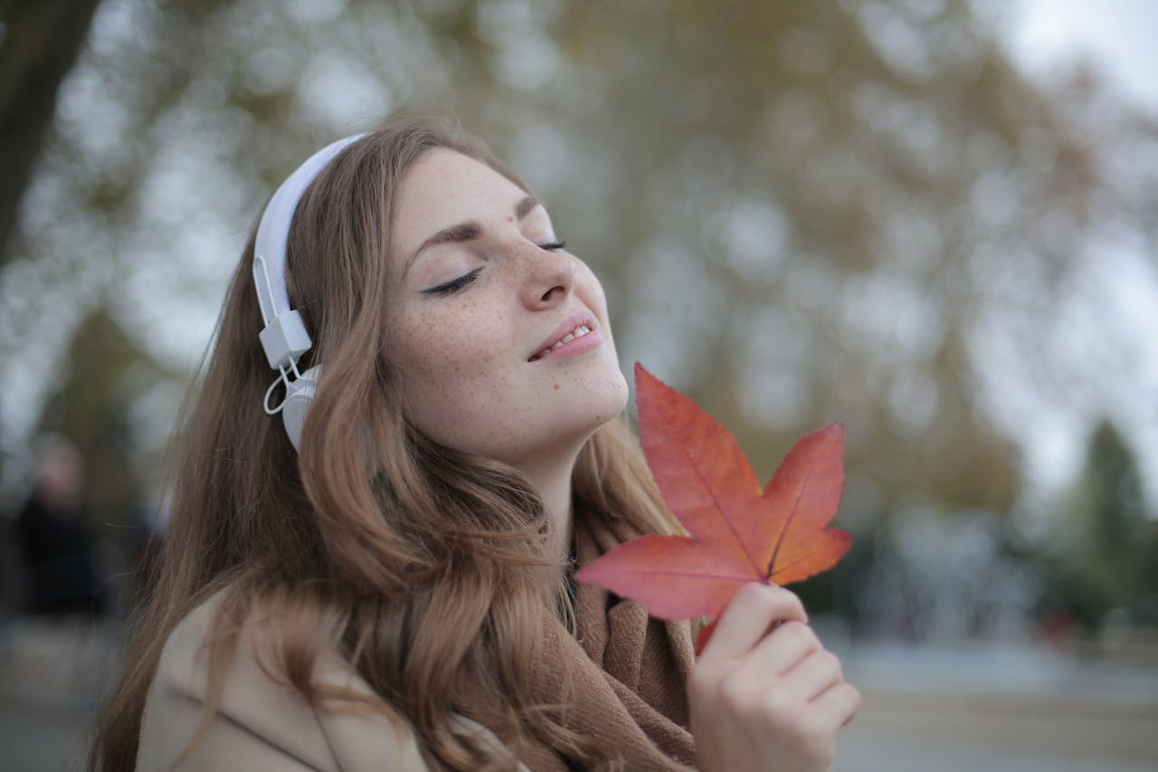 A woman listening to headphones holding a leaf